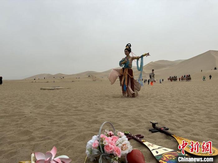 圖為2023年4月底，敦煌大漠“逐舞者”奧楠在鳴沙山月牙泉景區(qū)視頻直播敦煌舞?！●T志軍 攝
